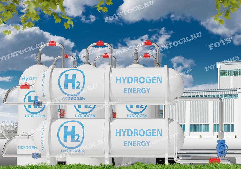 Фотография изображает водородные резервуары с надписью "H2" и "Hydrogen Energy" на фоне голубого неба и промышленного здания. Этот снимок подчеркивает важность использования водорода как экологически чистого источника энергии в промышленной сфере.